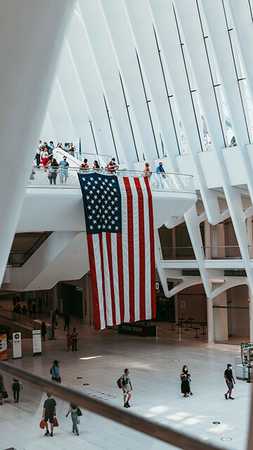 The interior of a tall building with white beams and a hanging American flag