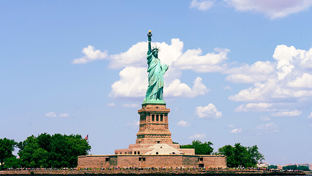 the statue of liberty with a blue sky and fluffy clouds behind it
