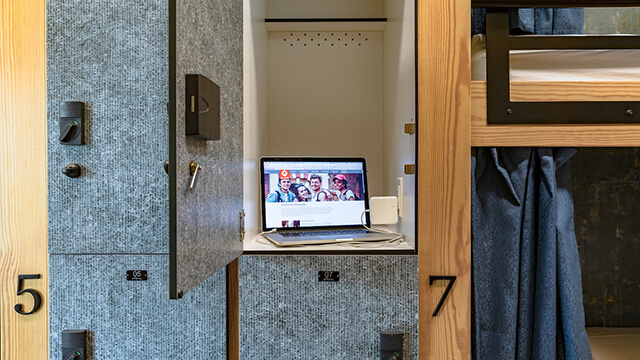 a laptop charging in a secure locker inside a HI USA hostel dorm room