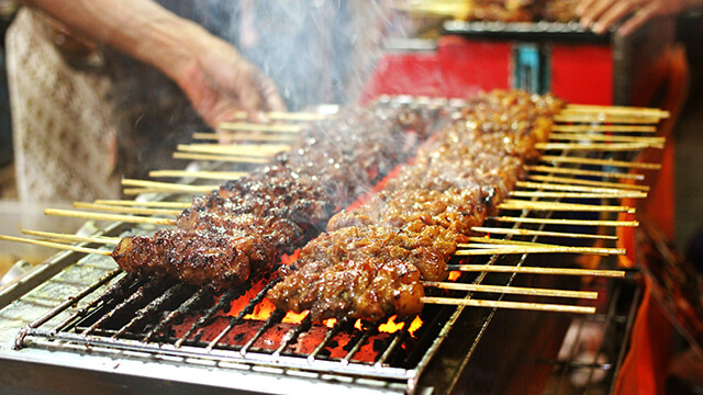 a grill with skewers of meat cooking 