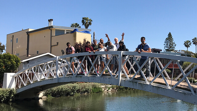 A group of travelers on a free HI USA walking tour stand on a bridge over a canal in Venice Los Angeles