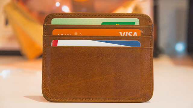 a slim brown wallet holding three credit cards