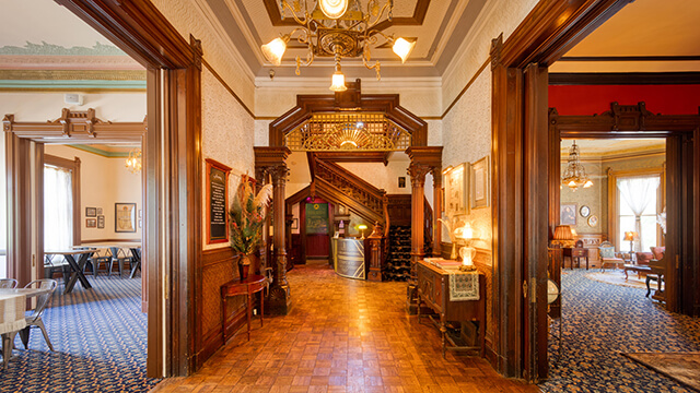 the entryway of HI Sacramento hostel, housed in a historic mansion in downtown sacramento, features chandeliers and a grand redwood staircase