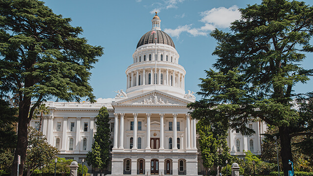 The California State Capitol is a grand white building with a dome surrounded by gardens. The Capitol is a short walk from HI Sacramento hostel.
