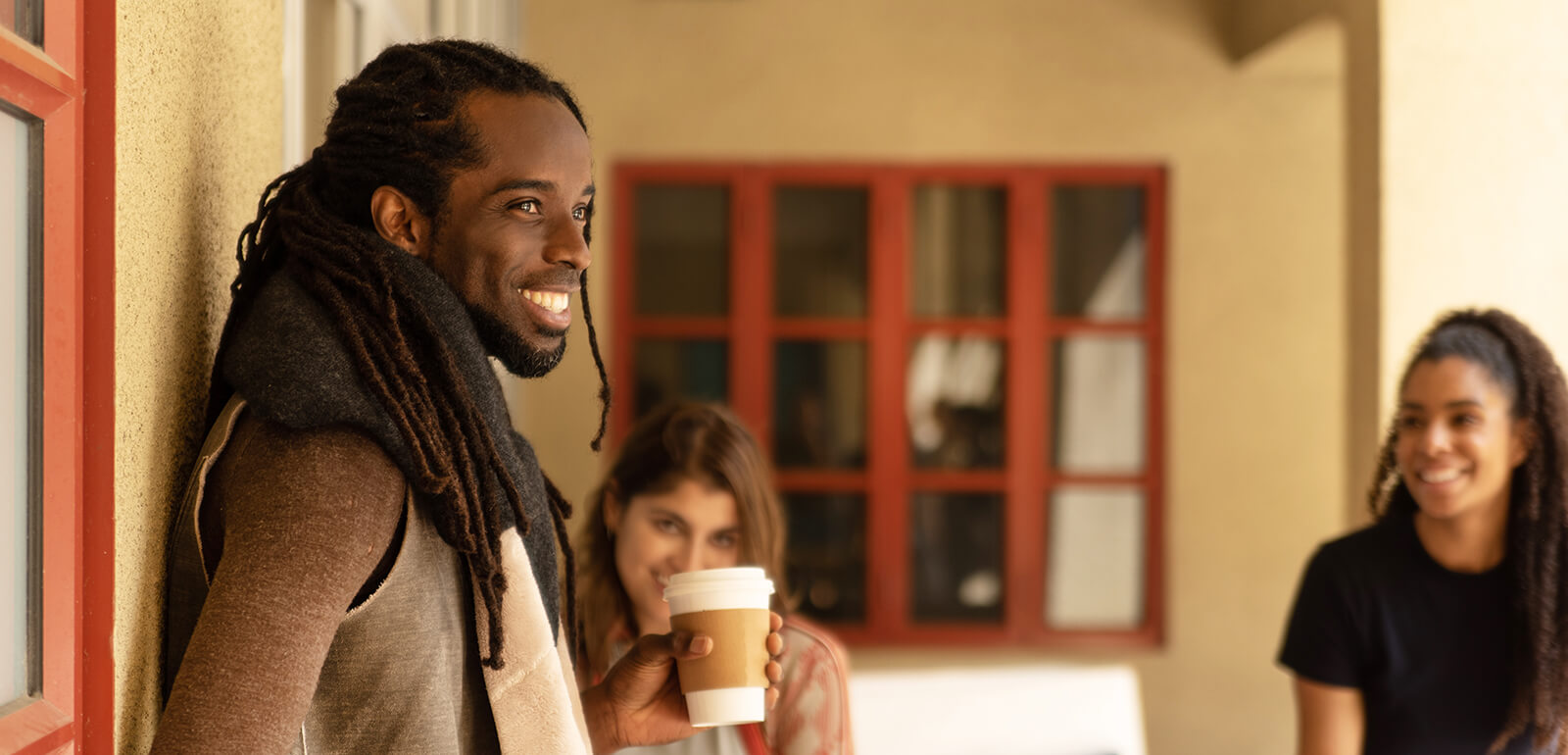 Three guests at a HI hostel stand outside talking