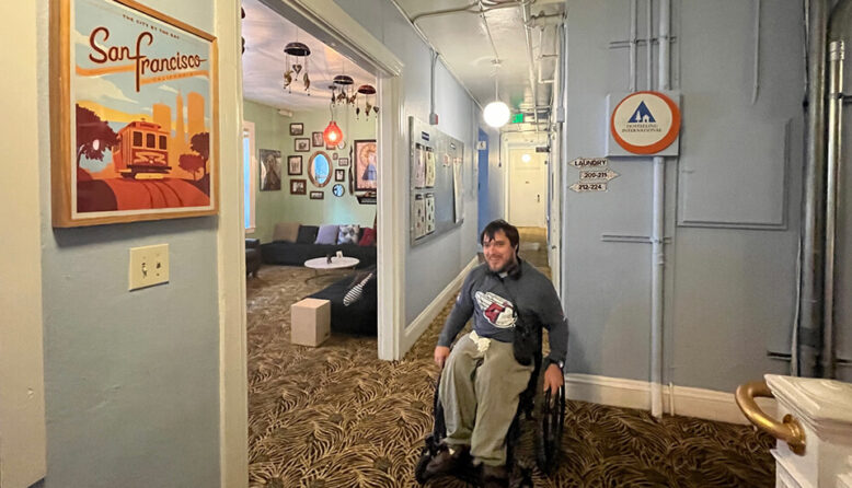 Peter Knab, who attended all 162 Cleveland Guardians games in 2023, sits in his wheelchair in the guest lounge of HI San Francisco Downtown hostel