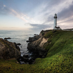 The historic Pigeon Point Lighthouse stands on a cliff at sunset on the grounds of HI Pigeon Point Lighthouse hostel.