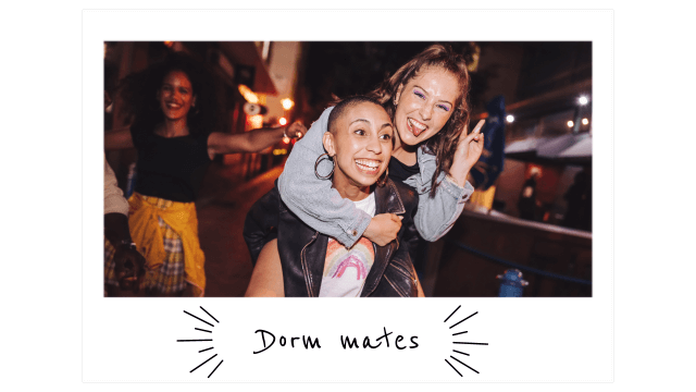 a young woman holds up her fingers in a peace sign while riding piggy-back on her friend's back on the street at nighttime