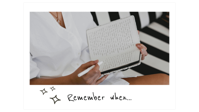 a polaroid of a woman in a white dress writing in a journal while sitting on a black-and-white-striped bench