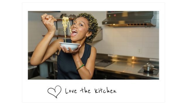 a young woman eats ramen in the kitchen at HI New Orleans hostel