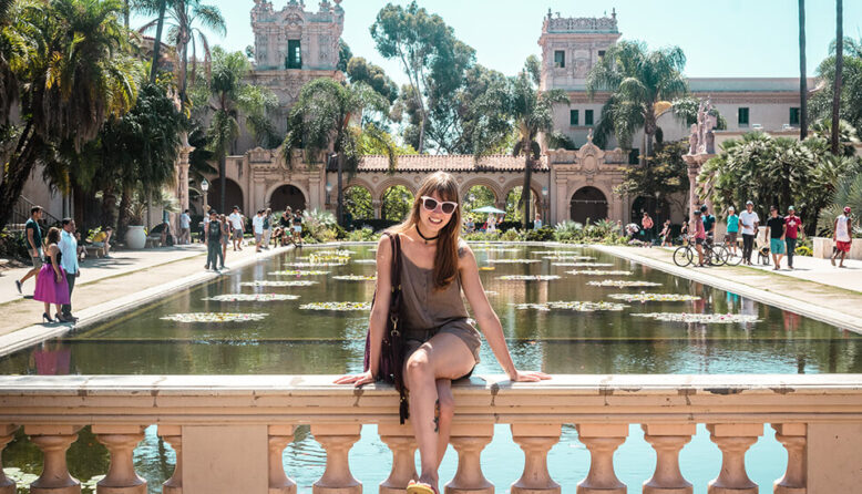 a young woman in sunglasses poses at Balboa Park in the sunshine