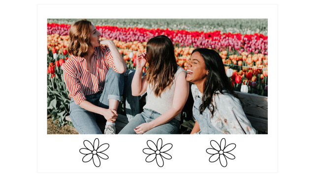 three women sit on a bench laughing in the middle of a fields of colorful tulips