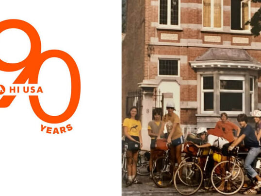 An old photo of a group of hostellers on bicycles in front of a large brick building. There is an orange graphic reading