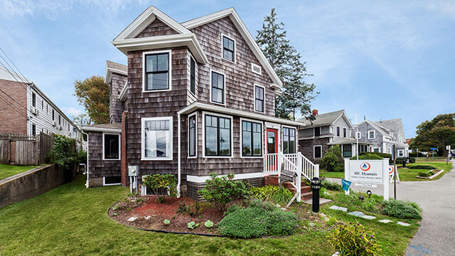 The exterior of HI Hyannis hostel, with a green lawn surrounding it.
