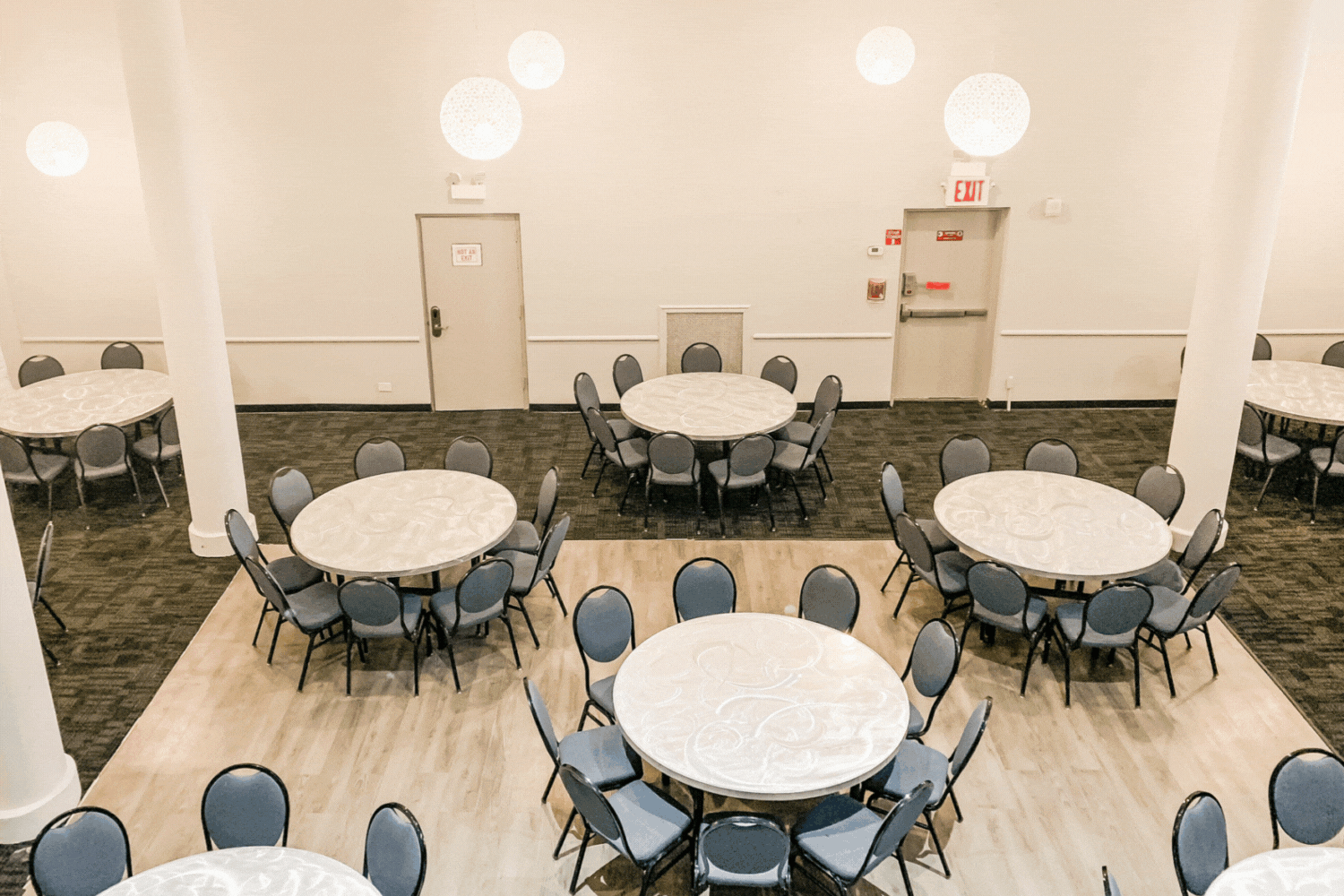 rotating images of the elegant and spacious SoHo room at HI New York, City. There are plenty of tables and chairs, high ceilings, and wood floors.