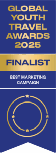 A blue and gold badge indicating HI USA's From Arrival to Belonging campaign status as a finalist for WYSETC's 2025 Global Youth Travel Awards in the "Best Marketing Campaign" category.