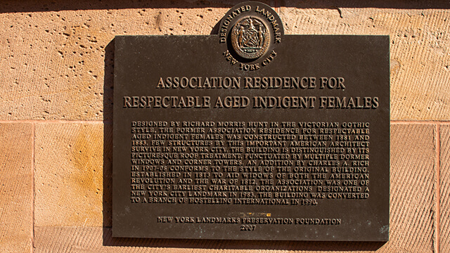 A plaque on the exterior of HI New York City hostel commemorating the building's design by Richard Morris Hunt and its years of service as a home for war widows. 