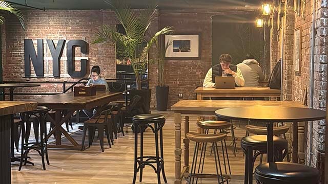 The New York Room at HI New York City hostel has high-top tables and seating with a relaxed, uncrowded atmosphere perfect for remote work. 