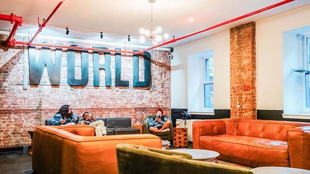 The World Room at HI New York City hostel has exposed brick walls, multiple comfortable couches, plenty of outlets, and windows letting in plentiful natural light. Its layout and reliable wifi make it perfect for digital nomads and others working remotely while traveling. 