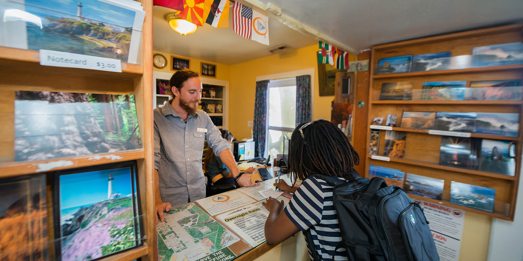 A guest with a backpack checks in at the front desk at HI Pigeon Point Lighthouse hostel