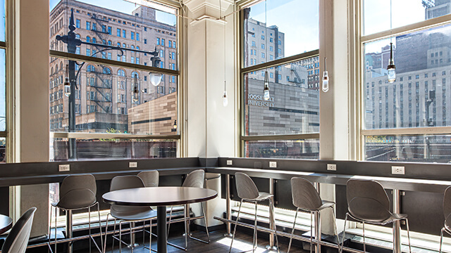 High-top window counters with individual power outlets overlooking the city at HI Chicago hostel.