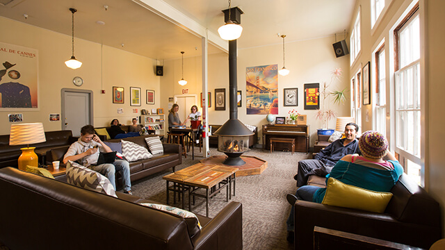 Guests working on laptops in the cozy fireside lounge at HI San Francisco Fisherman’s Wharf hostel.