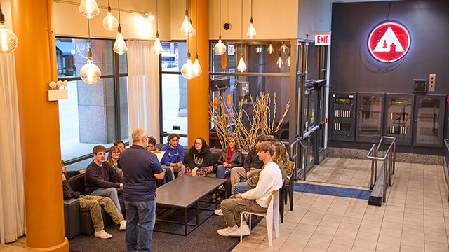 A group of students with their group leader meet in the lobby of HI Chicago hostel